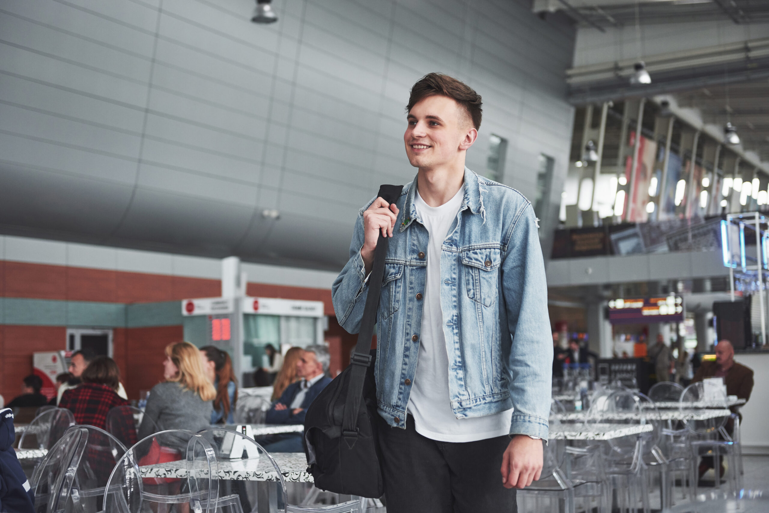 Young handsome man with a bag on his shoulder in a hurry to the airport.